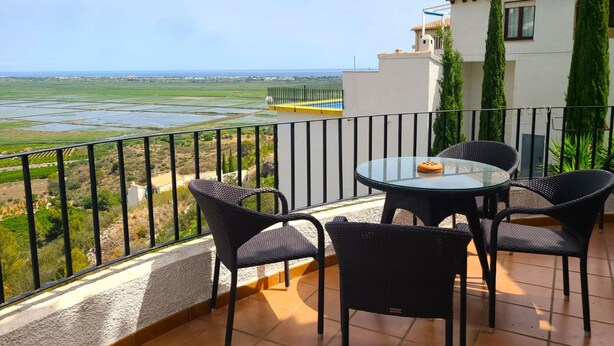 A balcony with a glass table and chairs, overlooking a coastal landscape with fields and a fence. - Villa LOS TULIPANES in Monte Pego (Pego)