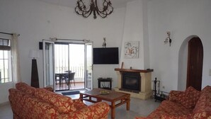 A living room with two sofas, a fireplace, a television, and a sliding glass door leading to an outdoor area. - Villa LOS TULIPANES in Monte Pego (Pego)