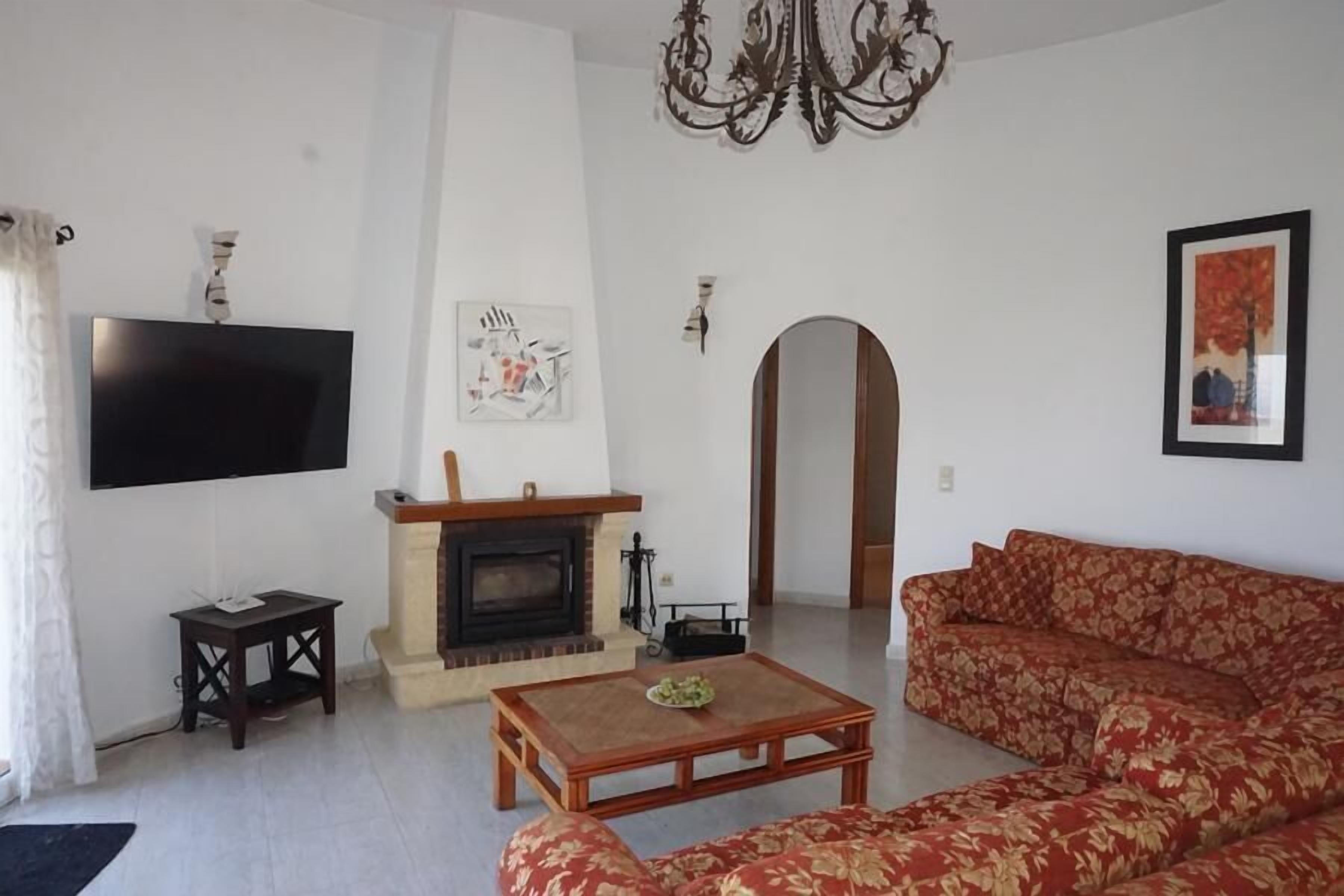 Un salon avec une cheminée, un canapé, une table basse et un téléviseur fixé au mur.