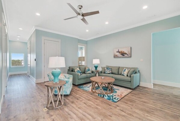 A living room with a sofa, two side tables, a coffee table, and a ceiling fan. - Beachfront with Heated Pool, Sleeps 24! (Gulf Shores)