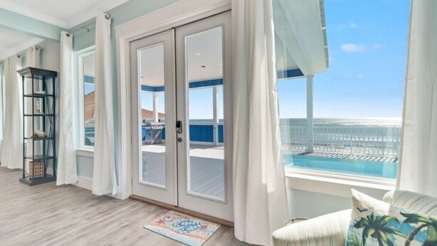 Un balcón amplio con vista al océano, una puerta corredera de vidrio y un pequeño espacio exterior con mobiliario.