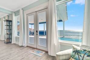 A spacious balcony with a view of the ocean, a sliding glass door, and a small outdoor seating area. - Beachfront with Heated Pool, Sleeps 24! (Gulf Shores)