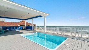 Zona de piscina con un deck techado, una estación de salvavidas y vista al océano.