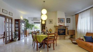 A spacious living room with a dining area, a fireplace, and a large window with curtains. - Villa with pool and sea view (Banjole)