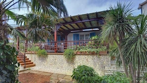 A stone-walled building with a wooden staircase leading to a covered porch. - Villa with pool and sea view (Banjole)