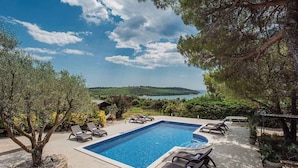 A rectangular swimming pool with lounge chairs and a view of a lake and hills. - Villa with pool and sea view (Banjole)