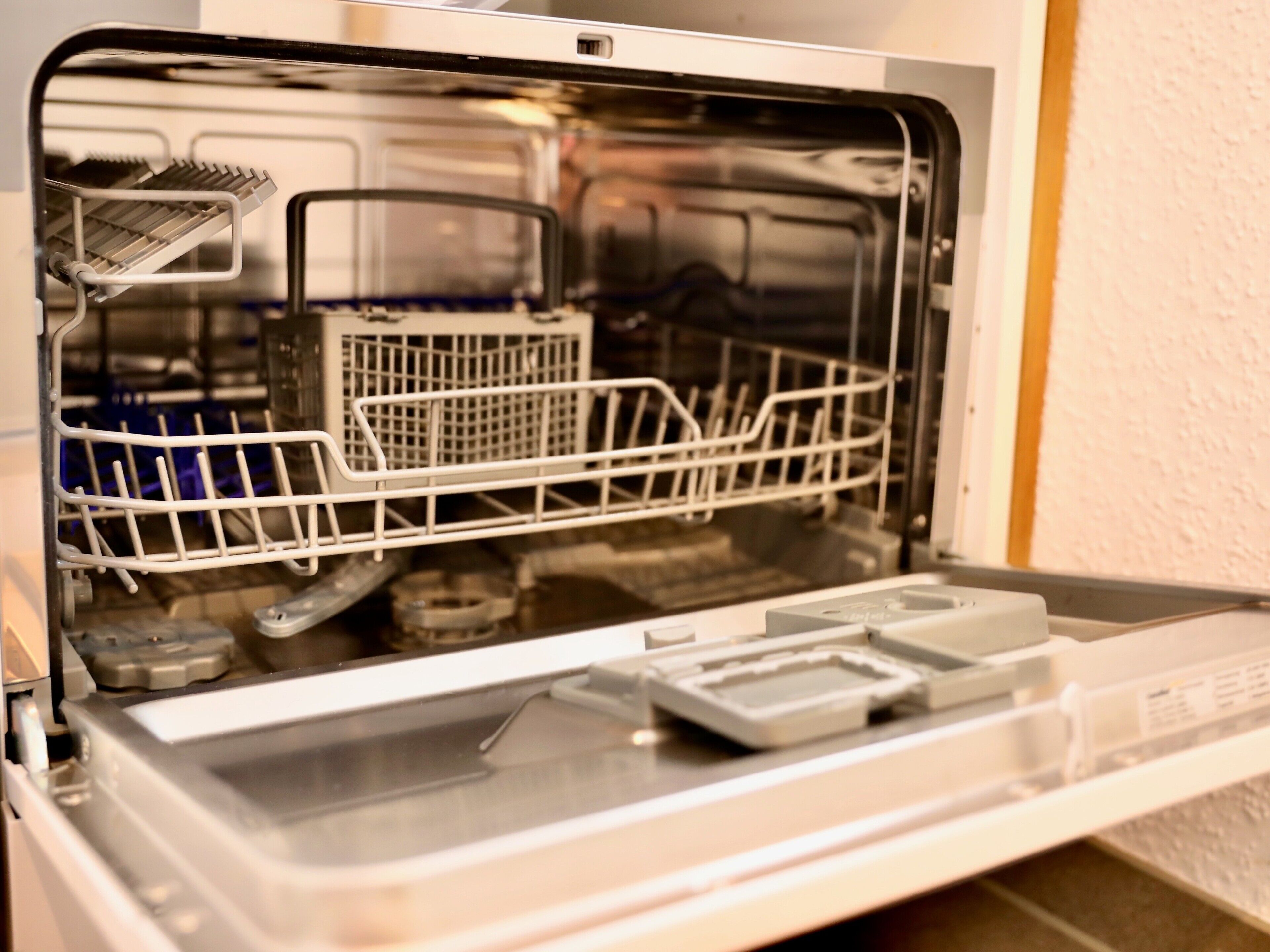 An open dishwasher with racks and a control panel.