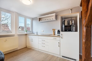 A modern kitchen with white cabinetry, a built-in microwave, and a window with a view of houses.