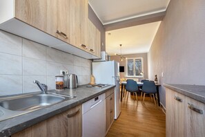 A modern kitchen with a dishwasher, double sink, and wooden cabinets.