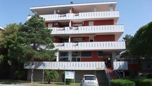 Un edificio a più piani con un'area di parcheggio di fronte.