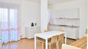 Una cucina compatta con mobili bianchi, un tavolo da pranzo con sedie e un angolo caffè.