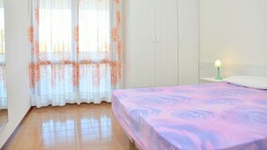 Una camera da letto con un letto, un armadio, un comodino con lampada e una finestra con tende.