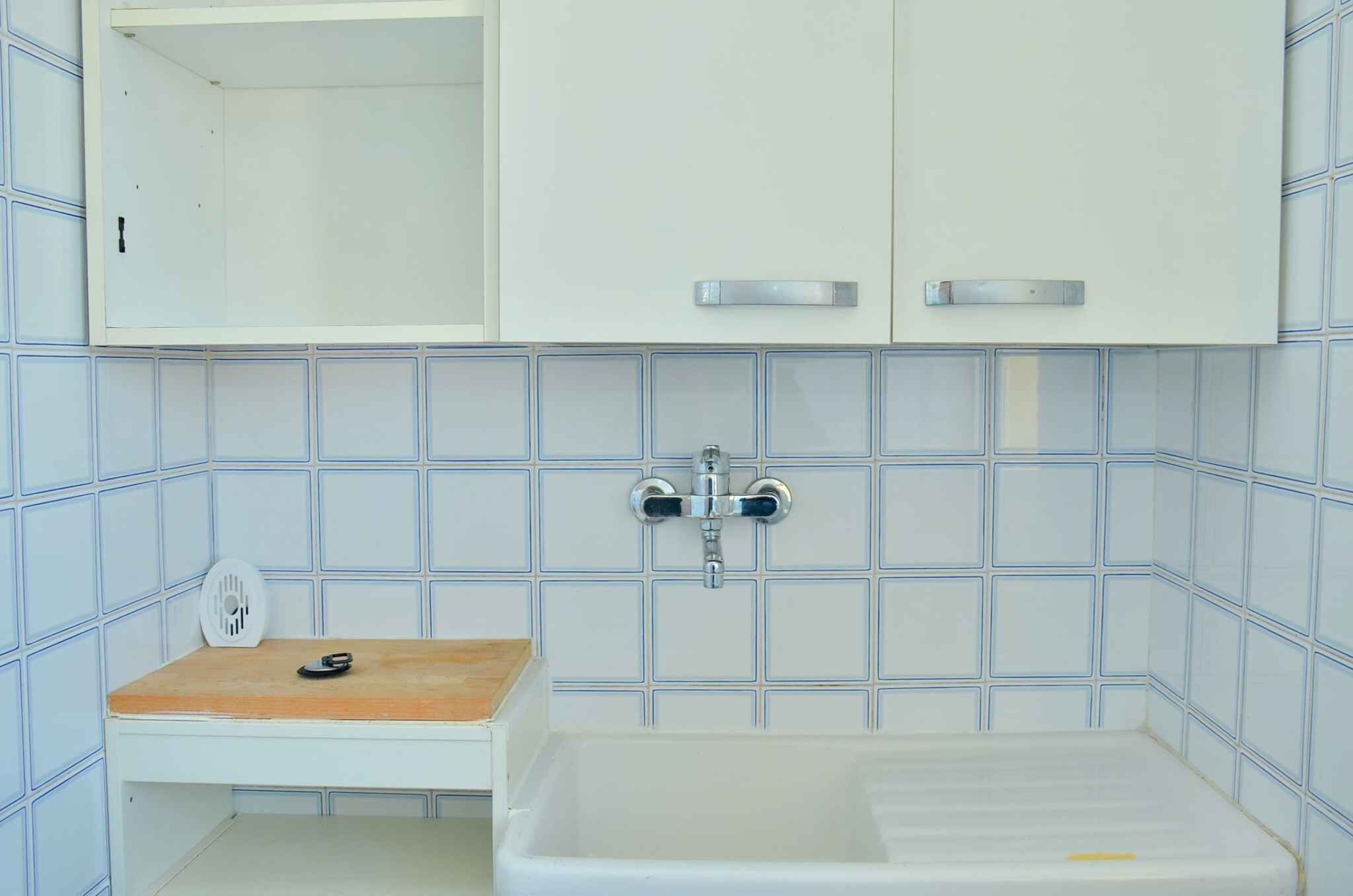 Un baño con lavamanos blanco, encimera de madera, espejo y bañera blanca.