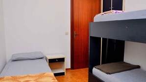 Ein Schlafsaalzimmer mit Etagenbetten, einem Holzschrank und einem kleinen Schreibtisch.