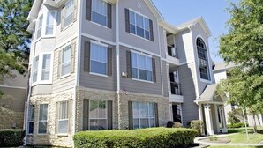 A multi-story residential building with a stone facade, multiple balconies, and a well-maintained lawn. - Serene Escape in the Pines- shopping, dining, entertainment-Iron Man (Spring)