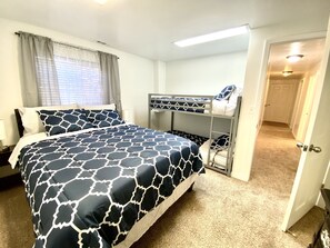 Un dormitorio con literas, una cama individual y piso alfombrado.