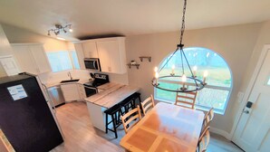 Une cuisine moderne avec des meubles blancs, un réfrigérateur noir et un coin repas comprenant une table et des chaises en bois.