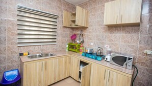 Une cuisine de taille réduite, équipée d’un évier, d’une cuisinière, d’un four à micro-ondes et de meubles de rangement en bois.