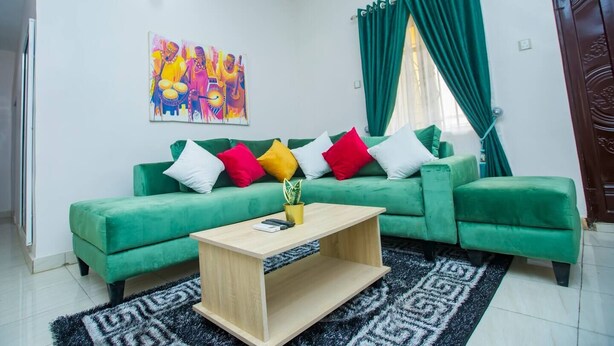 Un salon avec un canapé vert, une table basse en bois et un tableau coloré accroché au mur.