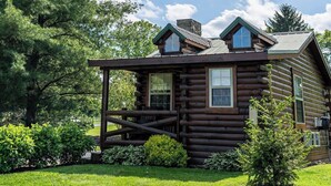 A log cabin with a porch, windows, and a chimney.
