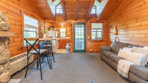 A log cabin interior with a kitchen, dining area, and living room.