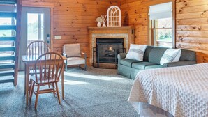 A log cabin interior with a fireplace, a sofa, a chair, and a bed. - Spacious 6BR Retreat in Amish Country (Millersburg)