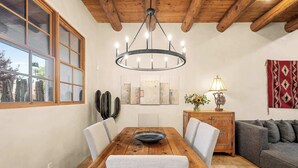 A dining area with a wooden table, chairs, a chandelier, and a sofa.