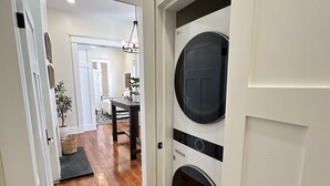 A hallway with wooden flooring leading to a laundry area with two large washing machines.