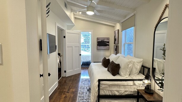 A bedroom with a bed, a ceiling fan, a nightstand, and a window.