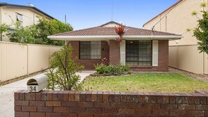 A single-story house with a brick facade, a tiled roof, and a front yard with a mailbox labeled '34'. - "Klinger House" - Redcliffe Q 4020 (Redcliffe)