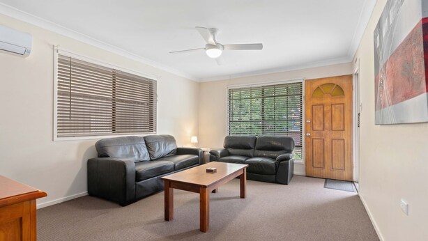 A living room with a sofa, a chair, a coffee table, a ceiling fan, and a door with a window. - "Klinger House" - Redcliffe Q 4020 (Redcliffe)