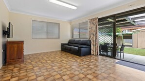 A living room with a black leather sofa, wooden cabinet, and a tiled floor. - "Klinger House" - Redcliffe Q 4020 (Redcliffe)