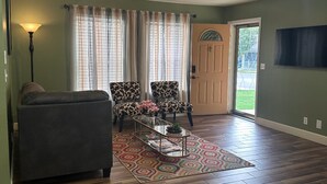 Una sala de estar con un sofá, dos sillones estampados, una mesita de centro y una alfombra decorativa.