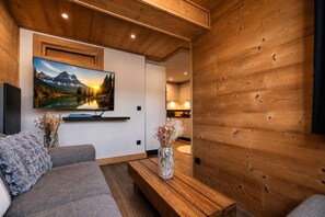 A modern living room with a flat-screen TV, a sofa, a coffee table, and a vase with dried flowers. - apartment for 4 people, very cozy and functional, renovated, mountain view, south facing,... (VAL THORENS)