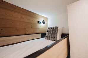 Ein Bett mit Holz-Kopfteil, ein Nachttisch und eine Wandleuchte.
