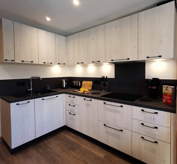 Een koelkast, een oven, een broodrooster, kookgerei, borden en bestek