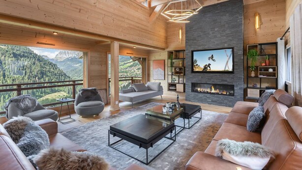 Amplia sala de estar con chimenea, televisor grande y vistas a las montañas.