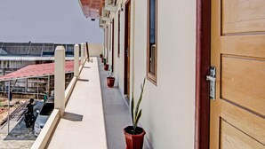 A balcony with potted plants, a wooden door, and a view of a construction site. - OYO 92135 A3 Homestay Syariah Executive (Pekanbaru)