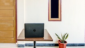 A laptop on a wooden table, a potted plant, and a door with a number 5 sign. - OYO 92135 A3 Homestay Syariah Executive (Pekanbaru)