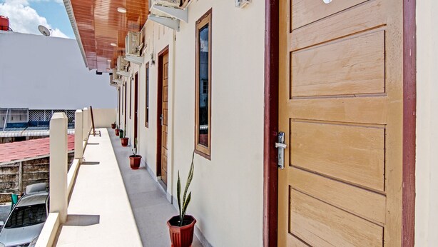 A hotel corridor with wooden doors, numbered 6, and potted plants. - OYO 92135 A3 Homestay Syariah Executive (Pekanbaru)