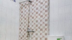 A bathroom with a checkered floor, a shower with a patterned wall, and a toilet with a green sticker. - OYO 92135 A3 Homestay Syariah Executive (Pekanbaru)