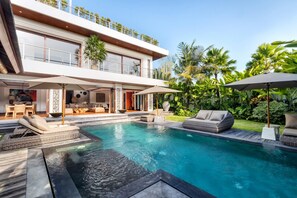 A modern two-story house with a swimming pool, outdoor seating, and lush greenery. - Sundance Villa (Kerobokan)