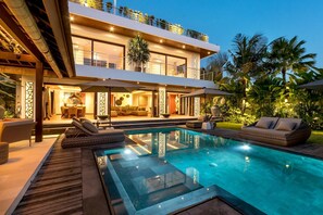 A modern two-story house with a swimming pool, outdoor seating, and lush greenery. - Sundance Villa (Kerobokan)