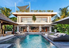 A modern two-story house with a swimming pool, outdoor seating, and a balcony. - Sundance Villa (Kerobokan)