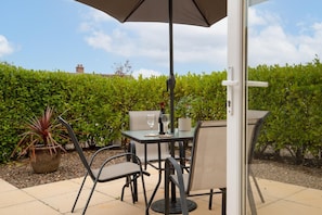 Eine Terrasse im Freien mit Tisch, Stühlen, einer Weinflasche und einem Glas.