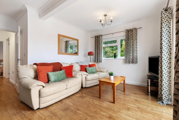 A living room with a beige sofa, a wooden coffee table, and a TV stand.
