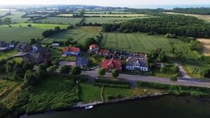 Ein Luftbild eines Flussdorfes mit Häusern, Feldern und einem Boot, das am Ufer liegt.
