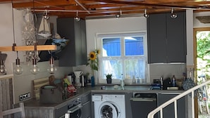 Eine kleine Küche mit Waschmaschine, Holzboden und einer Essecke mit Tisch und Stühlen.