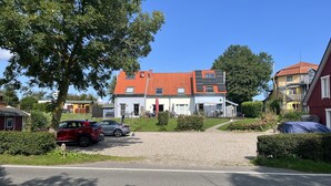 Ein Wohngebäude mit rotem Ziegeldach, Solaranlage und einer überdachten Außenfläche.
