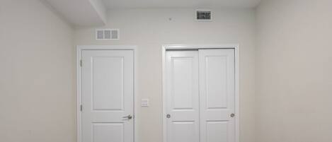 A bedroom with two white doors, a carpeted floor, and two beds.
